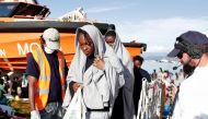 This handout picture taken and released by the Italian Red Cross on October 22, 2016 shows migrants landing in Vibo Marina, after a rescue operation in the Mediterranean Sea. Nine people drowned, ten were missing and nearly 1000 migrants were rescued off 