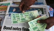A street vendor poses with new bond notes in the capital Harare, Zimbabwe, November 28, 2016. REUTERS/Philimon Bulawayo
