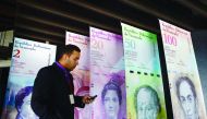 A man walks past banners showing Venezuela's currency, the bolivar, at the Central Bank of Venezuela (BCV) in Caracas. The BCV presented the new bank notes that will be in circulation from December 15, 2016, including a 20,000 bolivars bill.