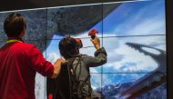 A woman climbs a mountain in a VR experience at the Tsinghua Tongfang exhibit booth during the 2017 Consumer Electronic Show (CES) in Las Vegas, Nevada, January 6, 2017. / AFP / DAVID MCNEW
