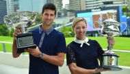 Reigning Australian Open Champions Angelique Kerber of Germany (right) and Novak Djokovic of Serbia carry the trophies ahead of the Australian Open draw ceremony in Melbourne, yesterday.