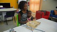 Telecommunications engineer Olivia Koburongo holds a baby in front of pneumonia-diagnosing 