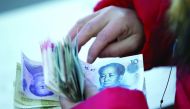 A woman counts Chinese yuan banknotes as she sells tickets for a job fair in Beijing.
