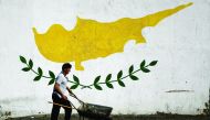 A man pushes a cart in front of a Cypriot flag painted on a wall in capital Nicosia, Cyprus, yesterday.