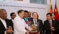 Sri Lanka's Minister of Ports & Shipping Mahinda Samarasinghe (C) exchanges souvenirs with Executive Vice President of China Merchants Port Holdings Dr. Hu Jianhua (3R) during the Hambantota International Port Concession Agreement at a signing ceremony in