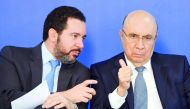 Brazilian Finance Minister Henrique Meirelles (R) listens to Planning Minister Dyogo Oliveira during the announcement of the distribution of the results of the workers' severance guarantee fund (FGTS) at the Planalto Palace in Brasilia, Brazil, on August 