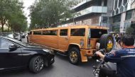 A car and motorcycle wait for a stretched Hummer limousine to go past outside a hotel in Beijing on September 8, 2017. AFP / Greg Baker