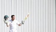 South African batsman Dean Elgar raises his bat and helmet as he celebrates scoring a century (100 Runs) during the first day of the first Test Match between South Africa and Bangladesh on September 28, 2017 in Potchefstroom, South Africa.  AFP / Gianluig