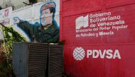 The logo of the Venezuelan state oil company PDVSA is seen next to a mural depicting late President Hugo Chavez at a gas station in Caracas, March 2, 2017 (Reuters / Carlos Garcia Rawlins) 
