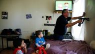Natalia Rollins children (L) Randy, 4, and Noah,2, watch television as Bob Friedl, a senior project manager with Environmental Management Solutions of New York Inc., checks lead levels with an X-Ray fluorescence detector at their apartment in the Coney Is