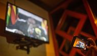 A man uses a mobile phone to record President Robert Mugabe's speech from a television while gathering at The Rainbow Towers in Harare on November 19, 2017. AFP