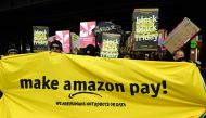 Protesters hold banners and placards during a demonstration to ask the online retailer Amazon to pay its employees fairly on November 24, 2017 on the 