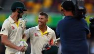 Australia's unbeaten batting pair David Warner (C) and Cameron Bancroft (L) walk back to the pavilion at the end of fourth day's play of the first cricket Ashes Test between England and Australia in Brisbane on November 26, 2017. AFP / Saeed Khan 
