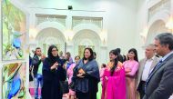Qatari artist Moudhi Al Hajri (left) explains about her works on display while Indian Ambassador P Kumaran (right), MAPS Qatar President and Founder, Rashmi Agarwal (middle) and other artists and guests look on at the opening of “The Colours of Desert Ser
