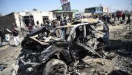 Afghan security personnel and civilians gather next to a damaged car at the site of a car bomb attack in Kabul on March 17, 2018. AFP / WAKIL KOHSAR

