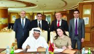 Sheikh Faisal bin Qassim Al Thani (left, sitting), Chairman of Aamal Company; and Bahar Sunman (right, sitting), member of the board of Simeks, signing agreement as other officials look on.