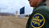 US Border Patrol officer Tekae Michael stands near prototypes of border wall proposed by US President Donald Trump on November 1, 2017 in San Diego, California (AFP / Frederic J Brown) 