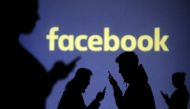 Silhouettes of mobile users are seen next to a screen projection of Facebook logo in this picture illustration taken March 28, 2018. REUTERS/Dado Ruvic/Illustration/File Photo
