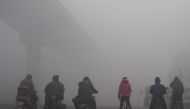 FILE PHOTO: Residents on their bicycles and electric bikes wait for the traffic at an intersection amid heavy smog in Shijiazhuang, Hebei province, China, December 10, 2015. REUTERS/Stringer/File Photo