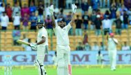 Indian cricketer Murali Vijay (L) looks on as teammate Shikhar Dhawan (C) celebrates his century (100 runs) during the first day of the one-off cricket Test match between India and Afghanistan at The M. Chinnaswamy Stadium in Bangalore on June 14, 2018. A