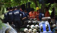 Thai rescue workers convene behind a large pile of oxygen tanks at the Tham Luang cave area as operations continue for the 12 boys and their coach trapped at the cave in Khun Nam Nang Non Forest Park in the Mae Sai district of Chiang Rai province on July 