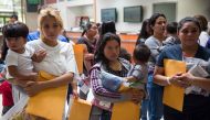 Immigrants wait to head to a nearby Catholic Charities relief center after being dropped off at a bus station shortly after release from detention through 