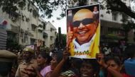 A Dravida Munnetra Kazhagam (DMK) party supporter holds a portrait of party president M. Karunanidhi (R) in front of hospital where he died, in Chennai on August 7, 2018. (AFP / ARUN SANKAR)