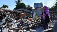  A woman and boy watch as men clear the wreckage of houses damaged by an earthquake in Menggala, North Lombok on August 8, 2018, three days after the earthquake struck the area. (AFP / ADEK BERRY)