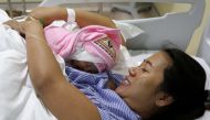Pan Ei Mon, the wife of detained Reuters journalist Wa Lone, embraces her newborn baby girl Thet Htar Angel in her hospital room in Yangon on August 10, 2018. AFP /Ann WANG 