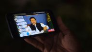 A Pakistani man holds his smartphone, as he watches a broadcast of a speech of newly appointed Pakistani Prime Minister Imran Khan, as he addresses the nation, in Karachi on August 19, 2018. (AFP / RIZWAN TABASSUM)