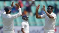India's Cheteshwar Pujara (L) and Ravichandran Ashwin (R) celebrate after the dismissal of West Indies batsman Keith Brathwaite during the third day's play of the first Test cricket match between India and West Indies at the Saurashtra Cricket Association