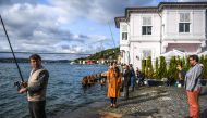 A fisherman watched by bystanders as he works beside waterside mansions on the Bosphorus River coast on the Asian side of Istanbul.  AFP / OZAN KOSE