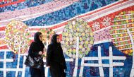 Two Iranian women walk along a street past a mosaic mural on Jaunary 14, 2017. AFP/Atta Kenare