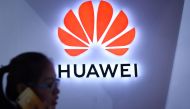FILE PHOTO: In this file photo taken on July 08, 2018 (FILES) In this file photo taken on July 8, 2018 a woman uses her mobile phone in front of a Huawei logo at Beijing International Consumer Electronics Expo in Beijing.  AFP / WANG ZHAO