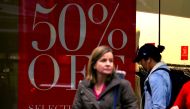 Shoppers walk in front of a retail shop displaying a sale sign in central Wellington, New Zealand, July 3, 2017. Reuters/David Gray
 