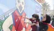 Qatari athlete Mariam Farid assists a young kid to fix a piece of the jigsaw puzzle that has the picture of Falah - the official mascot of the Doha 2019 World Athletics Championship, during the unveiling ceremony at Qatar Foundation’s Awsaj Academy, yeste