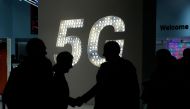 Visitors shake hands next to a 5G hotspot sign at the Mobile World Congress (MWC) in Barcelona on February 27, 2019.  AFP / Pau Barrena  