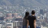 A couple sits and looks at Caracas on March 12, 2019 as a nationwide power blackout entered its fifth day.  AFP / Juan Barreto 