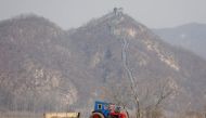 Farmers in a field as a section of the Great Wall is seen on the Chinese side of the Yalu River north of the town of Sinuiju in North Korea and Dandong in Chinese Liaoning province, April 2, 2017. Reuters/Damir Sagolj