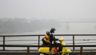 A Vietnamese woman wearing a face mask rides on a bridge amidst a blanket of smog over Hanoi on March 28, 2018. AFP / Manan Vatsyayana 