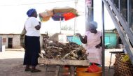 Mary Akinyi talks to a customer at her dried fish stall in Lindi village in Nairobi's Kibera slum, Kenya, March 26, 2019. Thomson Reuters Foundation/Wesley Langat