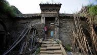 Tree trunks and rocks are set up to support a leaning wall of damaged cave house in an area where land is sinking next to a coal mine in Helin village of Xiaoyi, Shanxi province, China, August 2, 2016. Reuters 