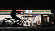 This photo taken on April 21, 2019 shows a cyclist passing a 7-Eleven convenience store at night in Tokyo. AFP / Charly Triballeau