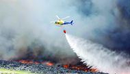 An helicopter throws water over a fire at a tire dump near a residential development in Sesena south of Madrid, May 13, 2016 Reuters/Sergio Perez