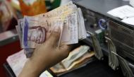 FILE PHOTO: A cashier counts Venezuelan bolivar notes in a state-run supermarket in Caracas January 9, 2015. Reuters/Carlos Garcia Rawlins