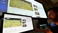 An IBM technician poses with screens showing IBM's AI-generated highlights of play on the sixth day of the 2019 Wimbledon Championships at The All England Lawn Tennis Club in Wimbledon, southwest London, on July 6, 2019.  AFP / Glyn Kirk