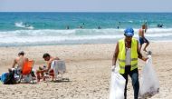 An employee of the Herzliya town hall collects plastics and other waste left behind by beachgoers, on one of the beaches of the Israeli coastal city on June 21, 2019.  AFP / Jack Guez 


 