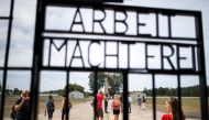 Visitors are seen through an iron gate carrying the German phrase 