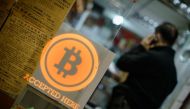 This file picture taken on February 28, 2014 shows a man talking on a mobile phone in a shop displaying a bitcoin sign during the opening ceremony of the first bitcoin retail shop in Hong Kong. AFP