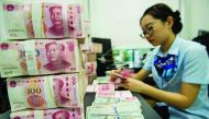 A Chinese bank employee counts 100-yuan notes and US dollar bills at a bank counter in Nantong in China's eastern Jiangsu province on August 28, 2019. AFP
